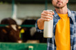 © LIGHTFIELD STUDIOS - cropped view of rancher in checkered shirt showing bottle of fresh milk, selective focus