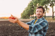 © LIGHTFIELD STUDIOS - farmer in plaid shirt looking at camera while holding ripe cherry tomatoes in cupped hands