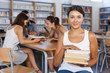 © JackF - Portrait of happy modern girl with books in hands sitting in classroom with studying fellow students