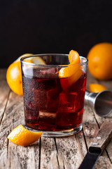 Boulevardier cocktail and orange zest on wooden table. Copy space	