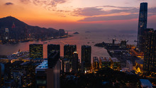 Aerial Scenery Panoramic View Of Hong Kong Evening With Metropolitan Bay Victoria Harbor At Sunset. Lighted Modern Cityscape, Urban Skyline Buildings. Energy Power Infrastructure. Popular Asian City