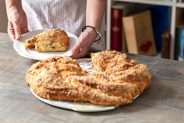 A large, round brioche bread and a slice one on a plate held by two female hands.