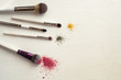 Makeup brushes with blusher and eyeshadow sample on white background