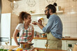 © Svitlana - Italian man, chef cook feeding his girlfriend, letting her taste the soup. Cheerful couple preparing a meal together in the kitchen. Cooking at home, Italian cuisine