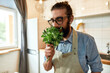 © Svitlana - Close up of young man, Italian cook in apron smelling basil leaves while getting ready to prepare a meal, standing in the kitchen. Cooking at home concept