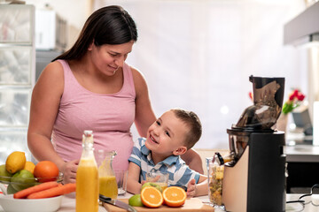 Canvas Print - Pregnant mother and her son making juice.