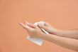 © New Africa - Woman cleaning hands with paper tissue on light brown background, closeup