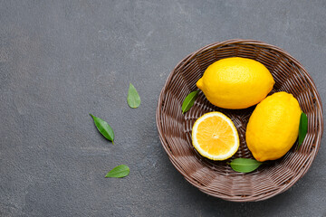 Wicker bowl with ripe lemons on grey background