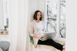 © contrastwerkstatt - Woman relaxing on a windowsill with her laptop