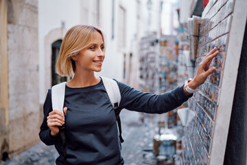 Wall Mural - Travel and shopping. Young traveling woman with backpacks choose magnets in souvenir shop in Portugal.