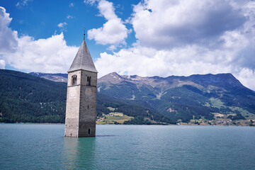 Beautiful view of the lake Resia. Famous tower in the water. Alps, Italy, Europe.