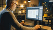 © Gorodenkoff - Creative Middle Aged Mobile Software Designer Sitting at His Desk Uses Desktop Computer with Screen Showing Smartphone Application Design Process. Stylish Modern Studio Office