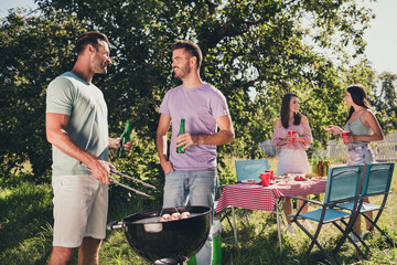 Poster - Photo of best fellows want have fun summer weekend dinner guys drink bottle beer cook sausages girls speak under green tree outside countryside