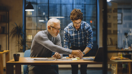 Poster - Chief Creative Designer Discusses Design Sheets with Young Developer. Two Professionals Having Discussion, Working with Documents, Choosing Right Concept. Evening in the Stylish Modern Studio Office