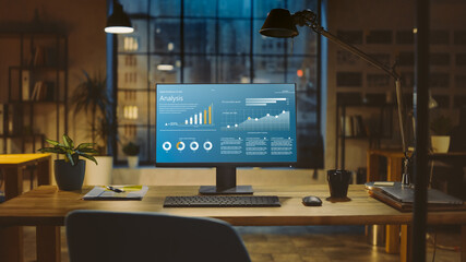 Poster - Shot of a Desktop Computer with Statistics Graph, Chart and Various Data, Showing Company Growth and Success. In the Background Warm Evening Lighting and Open Space Studio with City Window View.