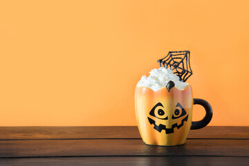 Wall Mural - Halloween cup of coffee garnish whipped cream and spider web on orange. Holiday horror treat. Space for text.