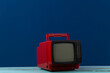 © splitov27 - Red retro old portable mini tv set on classic blue  background.