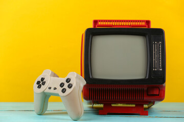 Wall Mural - Retrogaming. Video game competition. Old TV with gamepad on yellow background. Attributes 80s