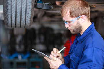 Wall Mural - A male auto mechanic in uniform is examining a tire while working in auto service