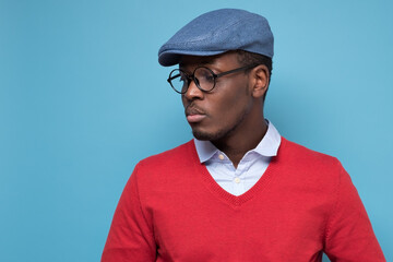 Wall Mural - Handsome african young man in blue cao and glasses thinking looking aside.