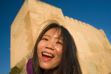 young happy and beautiful Asian Japanese tourist woman enjoying old castle tour in Spain during Europe holidays travel in wanderlust and tourism concept