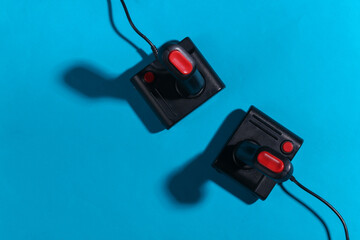 Wall Mural - Two retro joysticks on a blue background with a shadow. Retro gaming. Top view