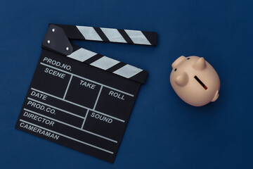 Wall Mural - Movie clapper board and piggy bank on classic blue background. Filmmaking, Movie budget, Entertainment industry. Color 2020. Top view