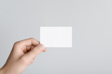 Business Card Mock-Up (85x55mm) - Male Hands Holding A Blank Card On A Gray Background.