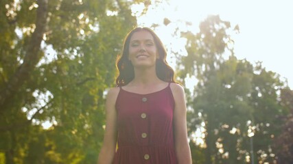 Wall Mural - leisure and people concept - happy smiling beautiful woman with long wavy hair walking along summer park