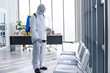© Pornsak - Disinfecting public place , Staff PPE uniforms suit are using an alcohol sprayer.