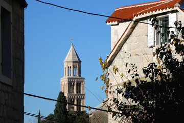 Picturesque street in Split, Croatia with traditional Mediterranean architecture and autumn leaves on the tree. Landmark Saint Domnius tower seen in the background. Selective focus.