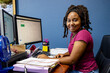 © SuperStock - A portrait of an African American woman at her call center desk and her headset on, working from home, looking into camera smiling.