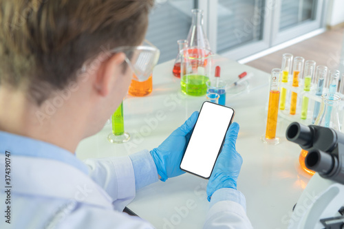 Fotografía A western scientist man holding blank space smartphone, working on test tube to analysis and develop vaccine of covid-19 virus in lab or laboratory in technology medical