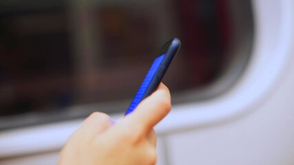 Poster - Close-up of the phone in the hands of a woman, scrolls the screen with her finger. Using a smartphone in public transport. Read an e-book.