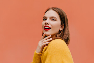 Curious woman in yellow outfit chilling in studio. Indoor shot of adorable caucasian girl with short hairstyle looking to camera with smile.