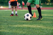 © gorynvd - Soccer player kicking ball on field. Soccer players on training session. Close up footballer feet kicking ball on grass.