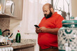 © Gener Vázquez - Hombre usando telefono inteligente en cocina