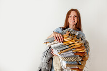 Happy Caucasian Woman Holding Bunch Of Wooden Hangers With Sorted Cotton And Wool Shirts.