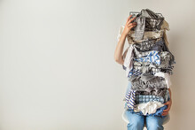 Surprised Woman Holding Metal Laundry Basket With Messy Clothes On White Background.