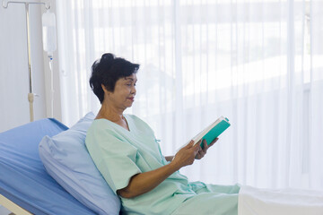 Poster - The elderly Asian women sat on the bed to read in the hospital.