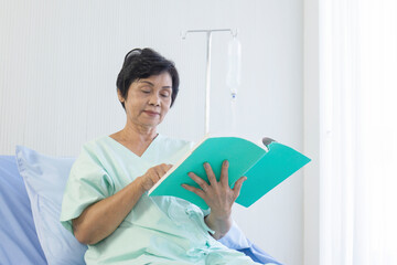 Poster - The elderly Asian women sat on the bed to read in the hospital.