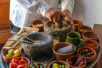 Chef preparing a traditional Pasilla Chile Sauce with all the ingredients in Oaxaca, Mexico. Focus on mortar, blur motion.