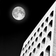 Surreal image of the Palazzo della Civiltà del Lavoro Eur Rome with full moon. Photo black and white.