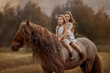 Two little sisters on red tinker horse Gypsy cob in summer evening field
