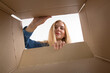 © Plutmaverick - Young beautiful girl blonde, opens and peeks into a cardboard box. To get or to put things to move, bottom view.
