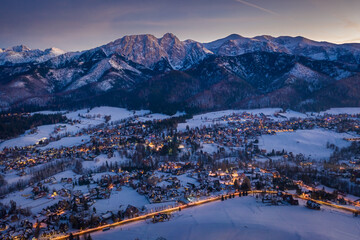 Wall Mural - Illuminated Zakopane city in winter after dusk, aerial view