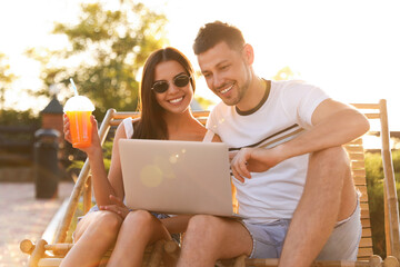 Canvas Print - Happy couple with laptop resting together outdoors