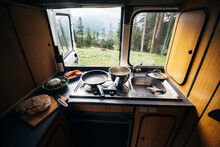 Interior Of Travel Camping Van Or Camper RV With Stove And Sink. Vanlife Lifestyle Vibes, Cooking On Campsite During Road Trip With Amazing View Of Mountains. Life On The Road In Converted Van