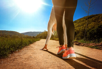 Photo of a fit girl with pink sneakers in start position for running.