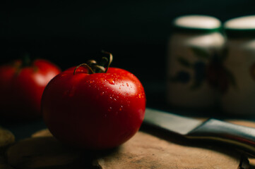 Red tomatoes on a black background, two steel knives and salts are lying nearby. High quality photo